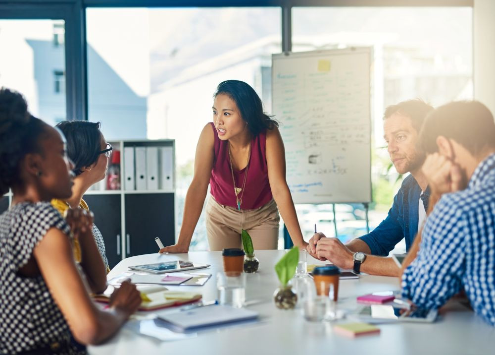 image of a woman leading a discussion at a small board table