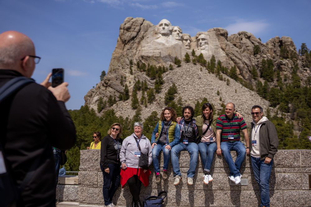 People posing for a photo in front of Mount Rushmore.