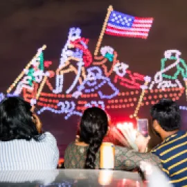 Family watches drone light show display on Fourth of July celebration