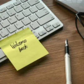A graphic of a computer keyboard with a Post-It reading Welcome Back on it.