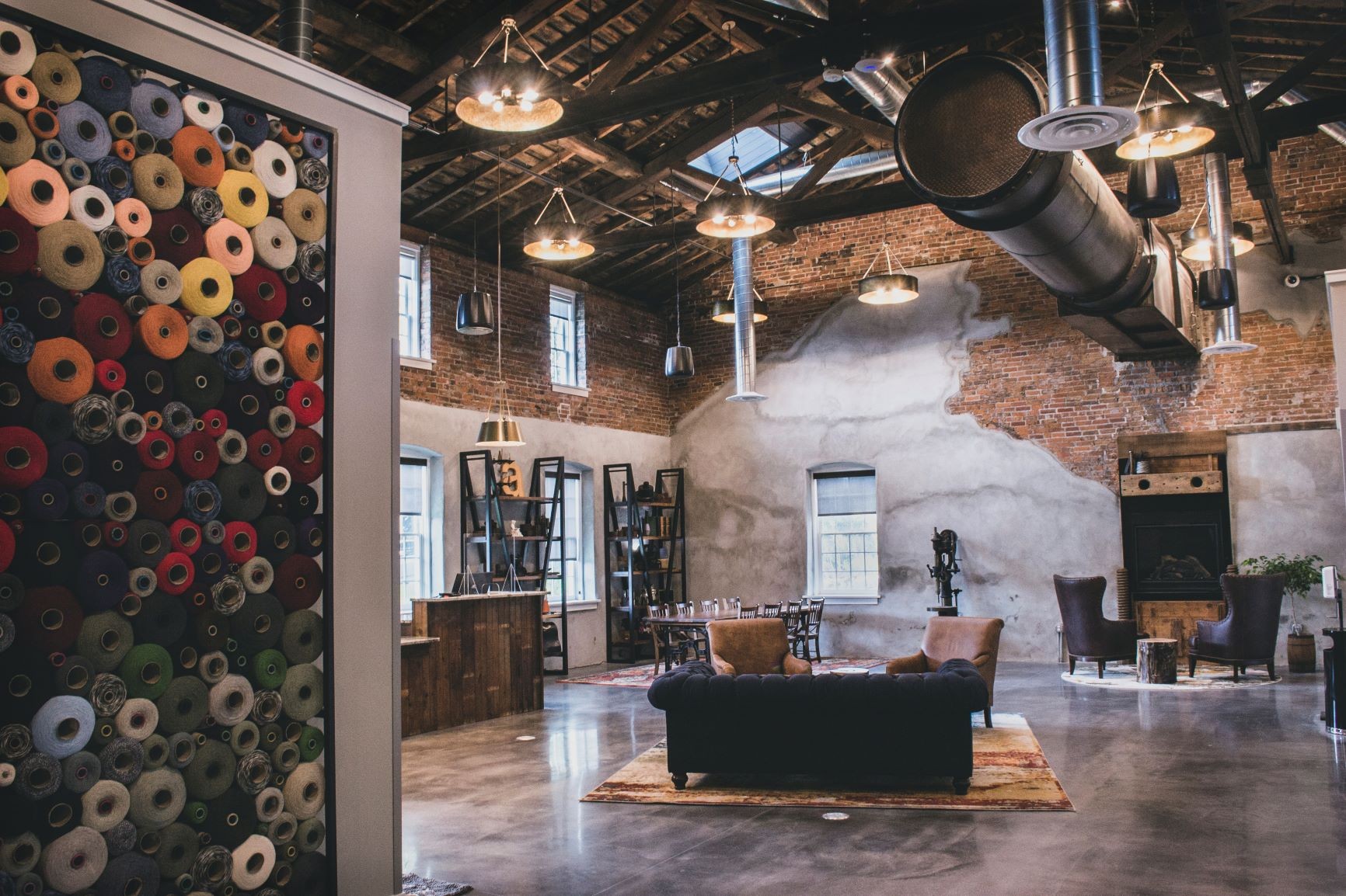 Photo: The hotel complex is uniquely Amana from the customer’s first step into the lobby. The design team incorporated old equipment from the mill. On the left, the yarn wall is a nod to the woolen production that still occurs on site. Credit: Sara Montgomery