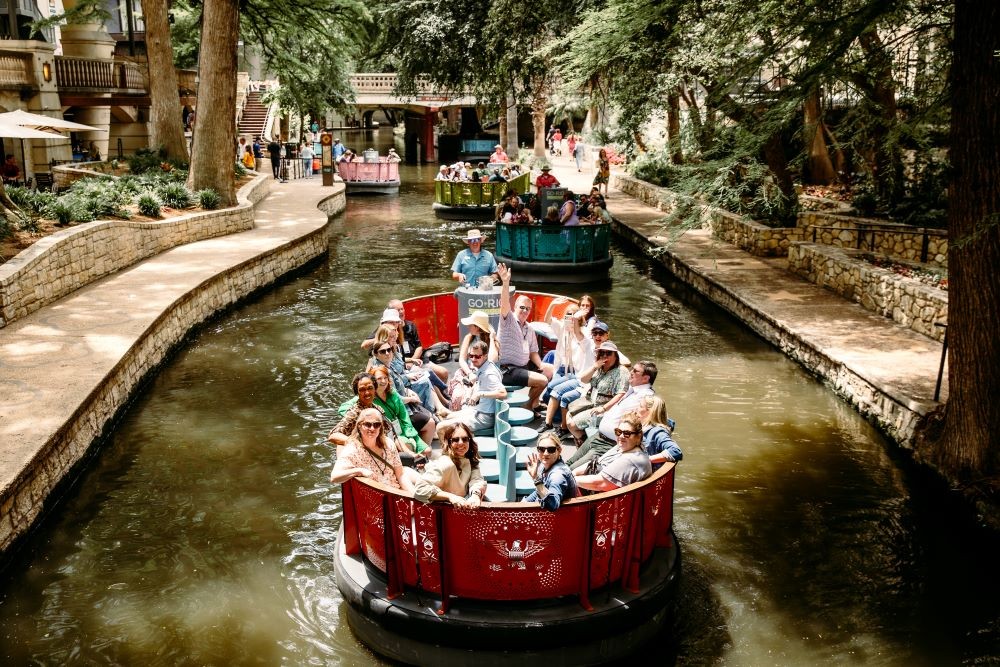 Meetings Today LIVE! attendees wave from sightseeing cruise down the River Walk’s San Antonio River
